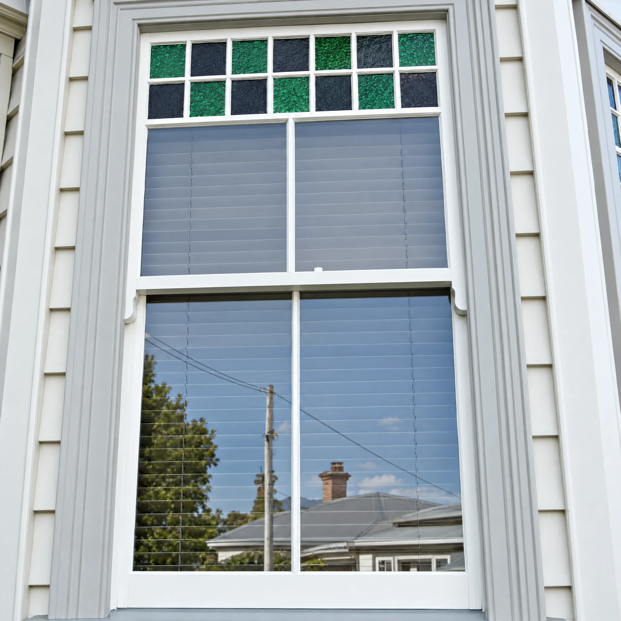 Timber double hung sash window with a coloured leadlight top light in a villa bay